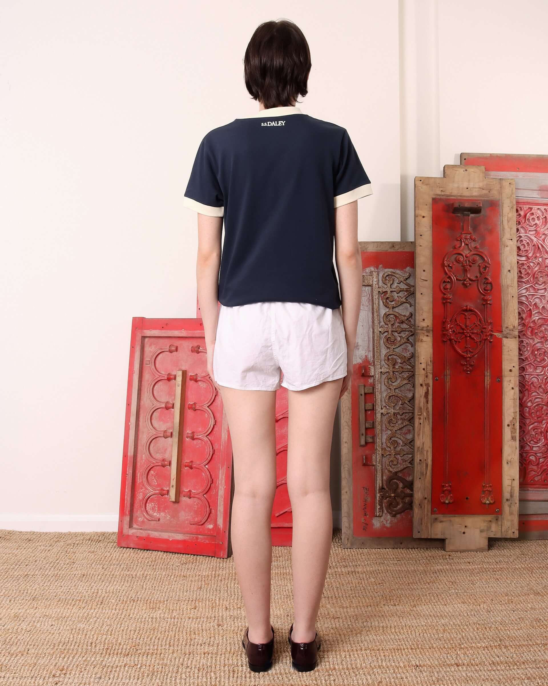 Model wearing the 'Tap' T-shirt in navy, showing the back of the garment and the intricate S.S.DALEY logo in ecru. 