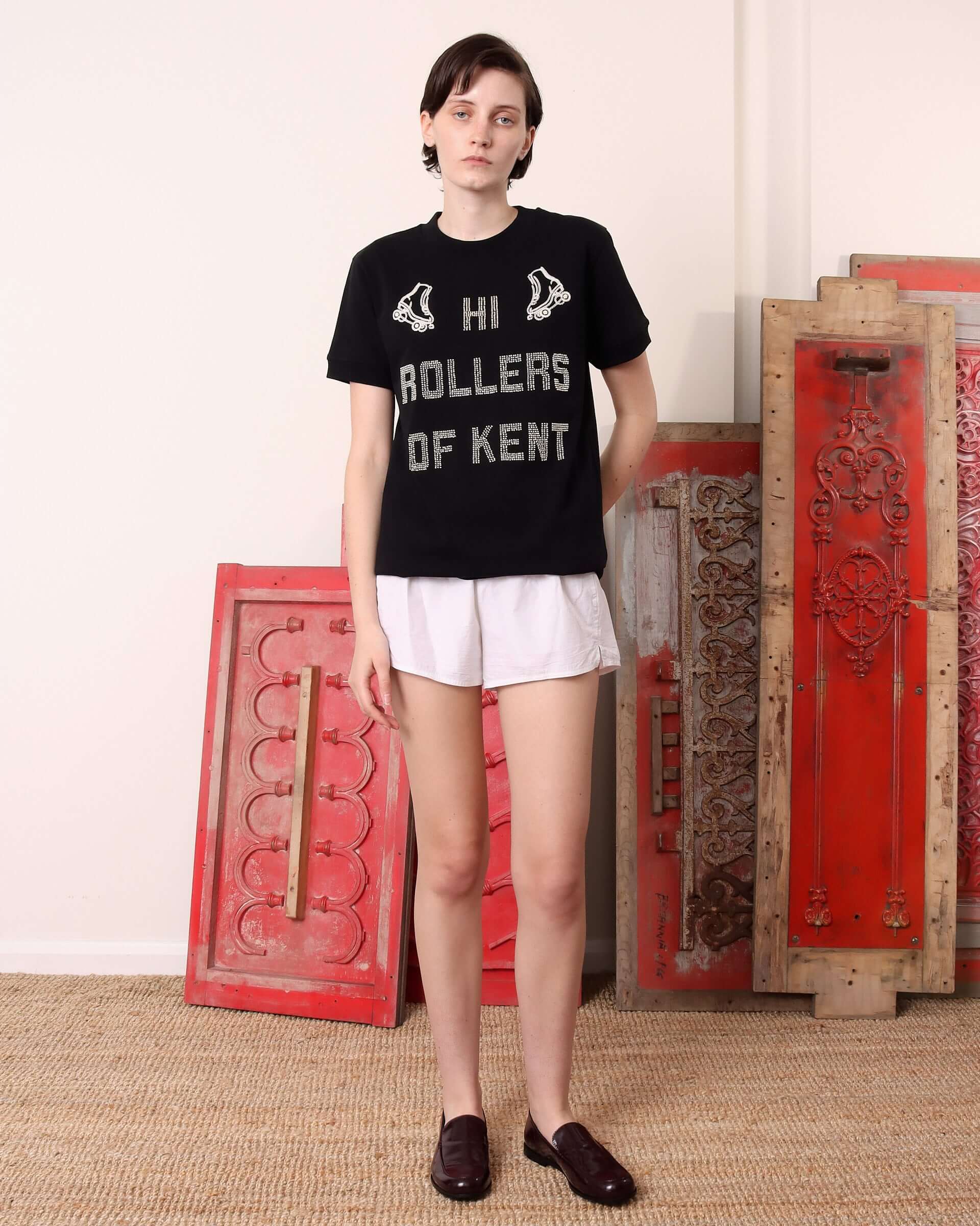 Black and ecru gender neutral tee with embroidered roller skaters and beaded graphics reading "Hi Rollers of Kent".