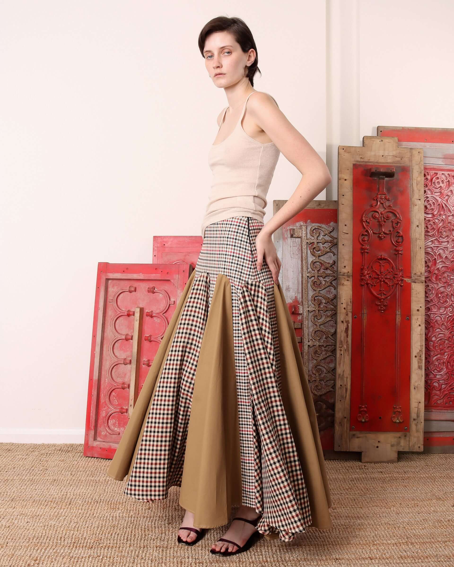 A model shows the movement of the eight alternating panels of the 'Taali' Skirt in check.