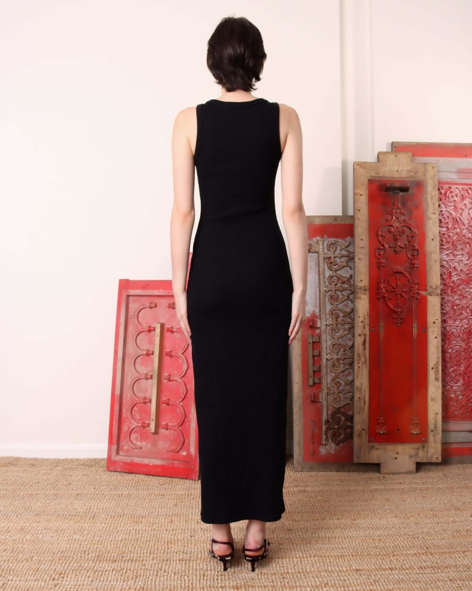 A model shows the back of the 'Lila' Jersey Dress on black, showcasing its maxi length and fitted style.