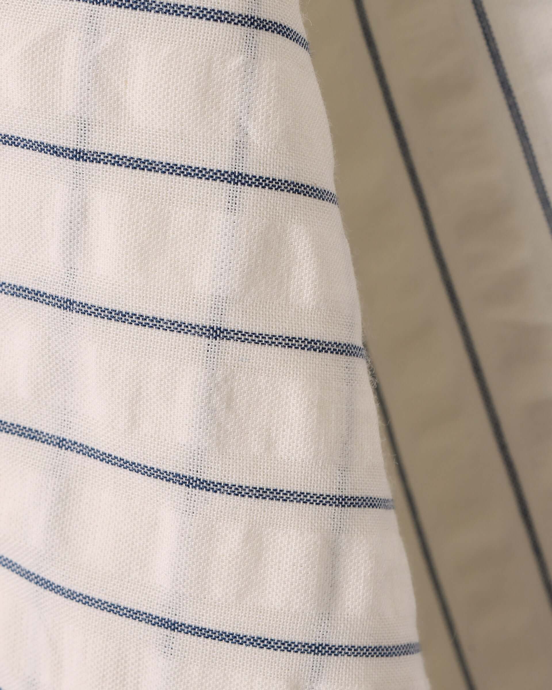 A detail shot of the woven navy blue pinstripe and white base seersucker fabric.