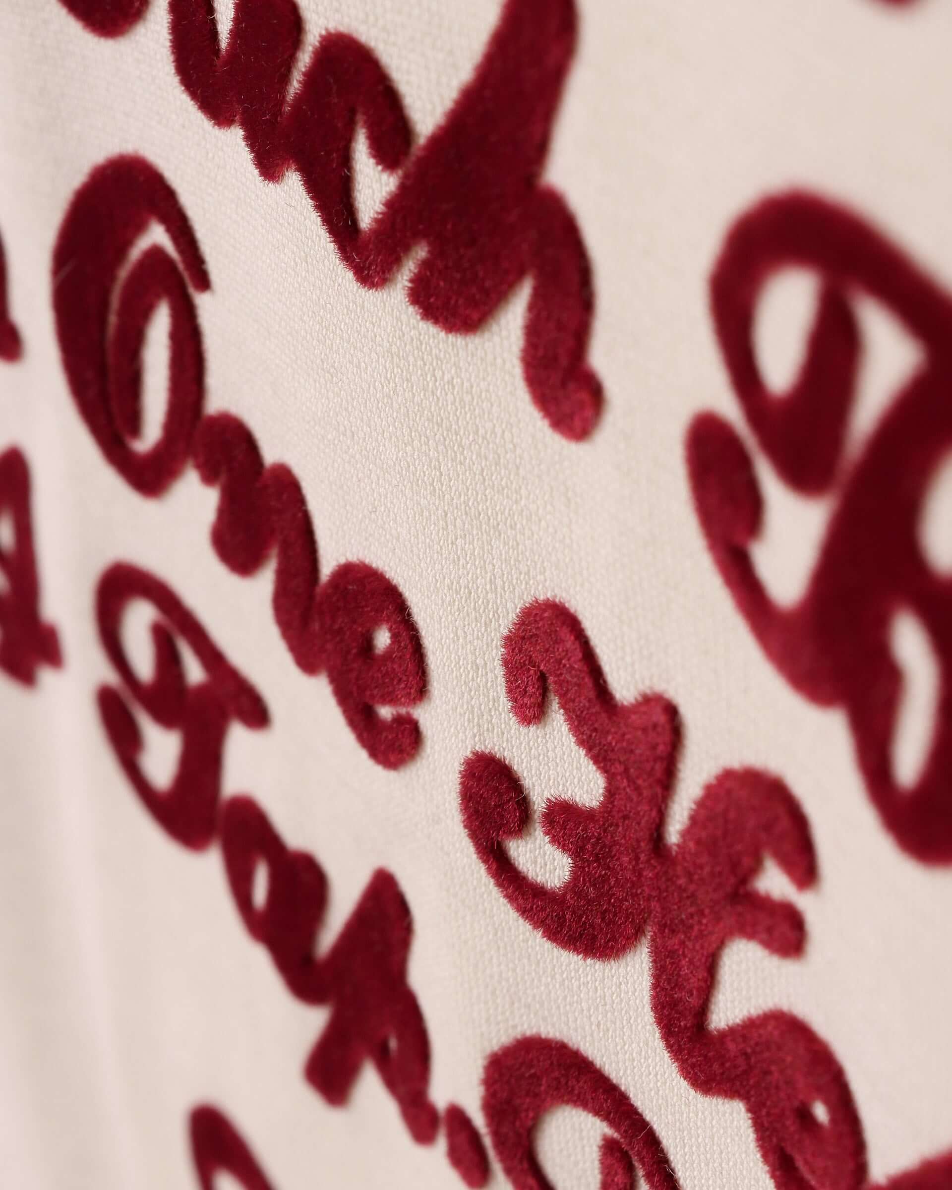 A detail shot of the burgundy slogan on the front og the t-shirt, showcasing the flocking technique creating a velvety texture.  