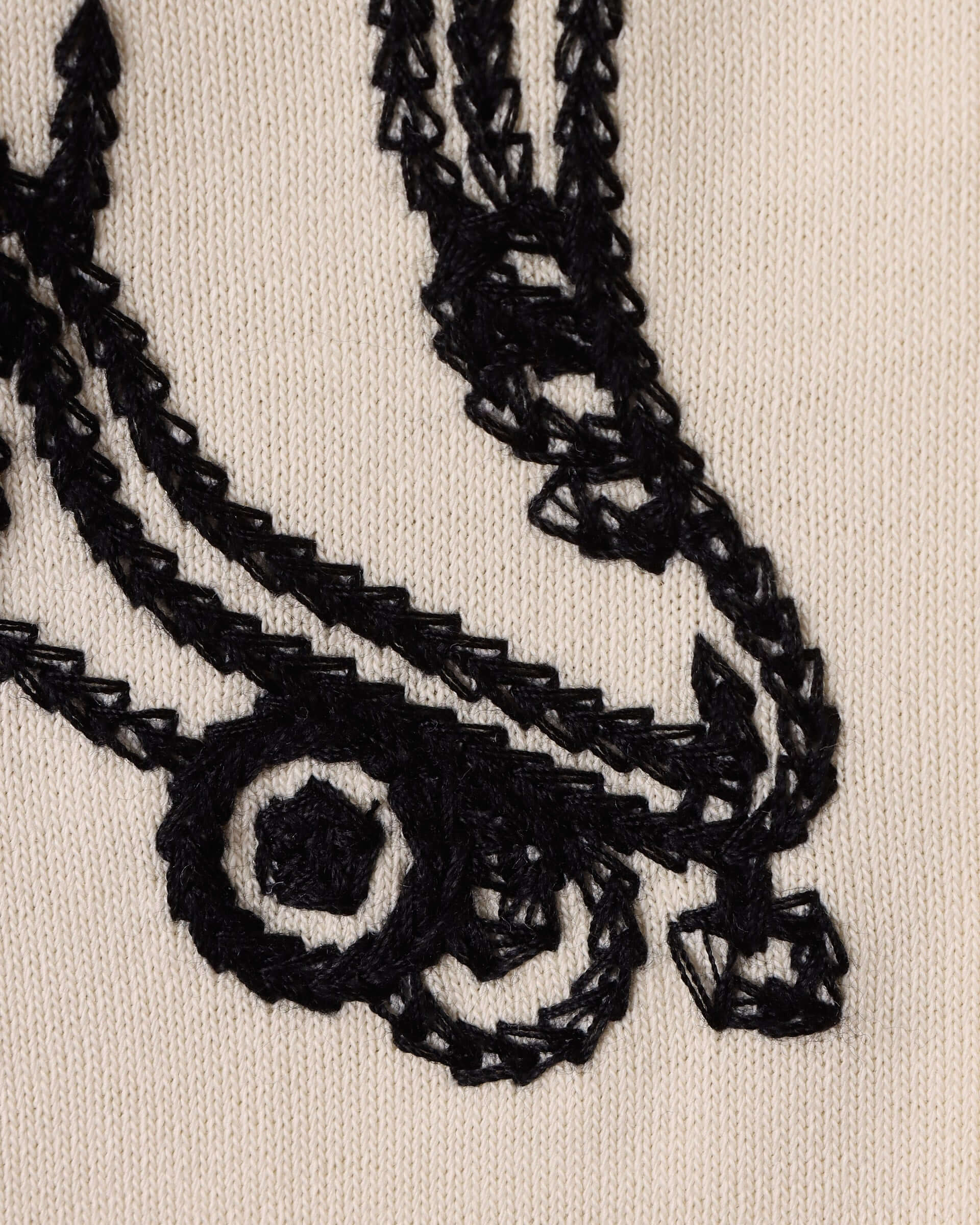 A detail shot on one of the embroidered black roller skates against the ecru jersey base.