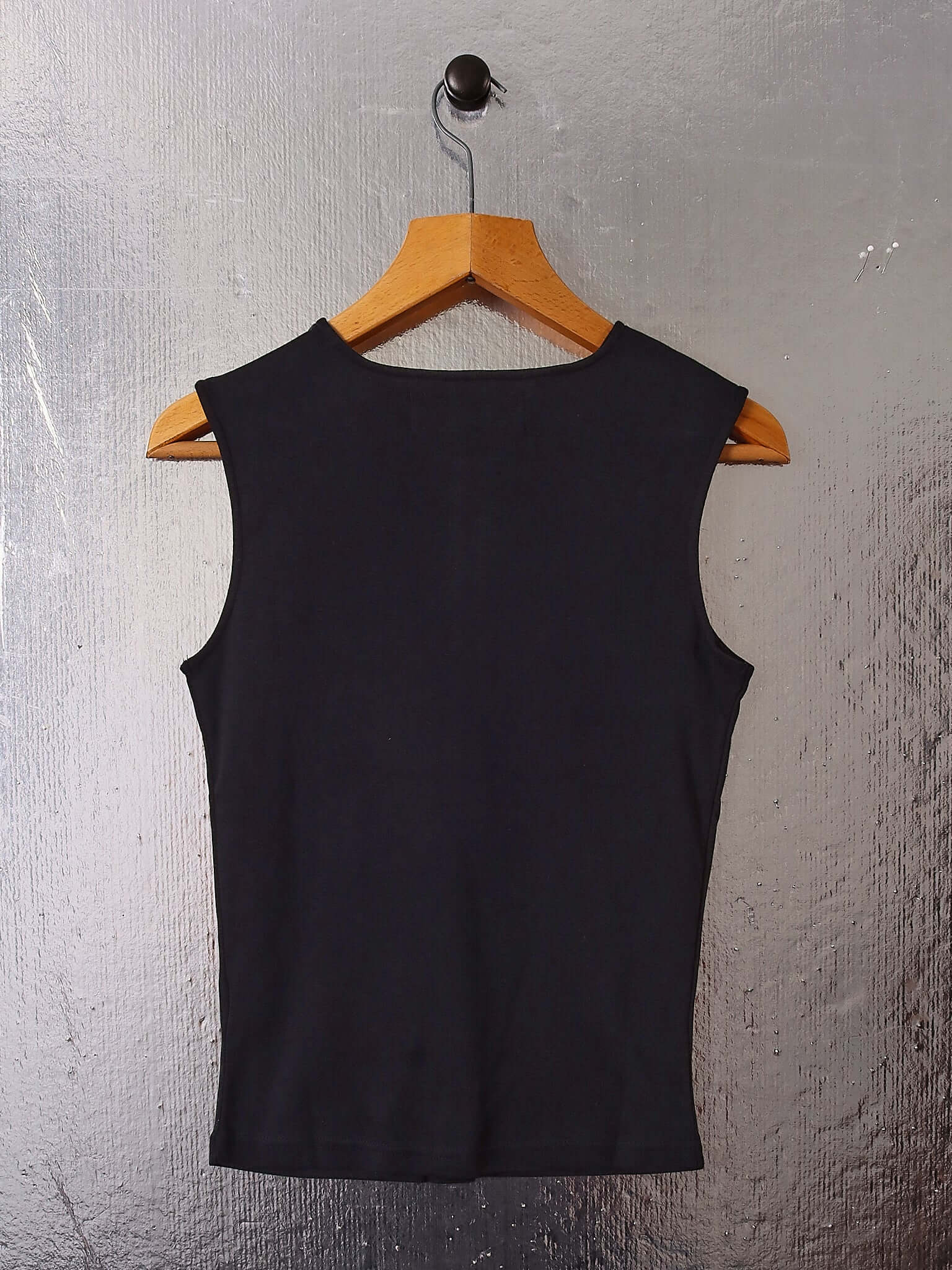 A flat shot of the back of the 'Cian' Buttoned Top in black on a hanger.