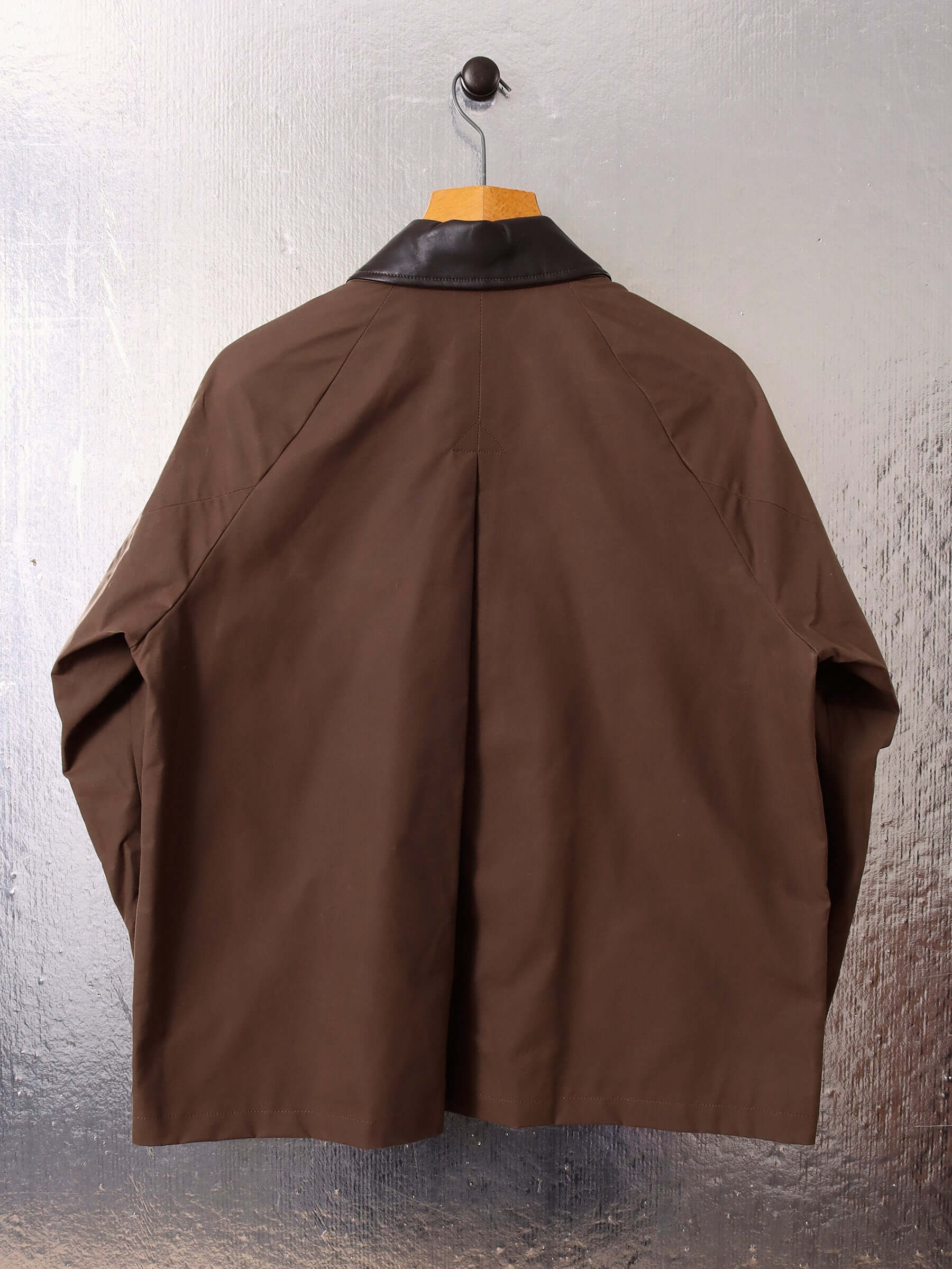 A flat shot of the 'Theodore' Waxed Blouson showing the pleat detail and dark brown Nappa leather collar.