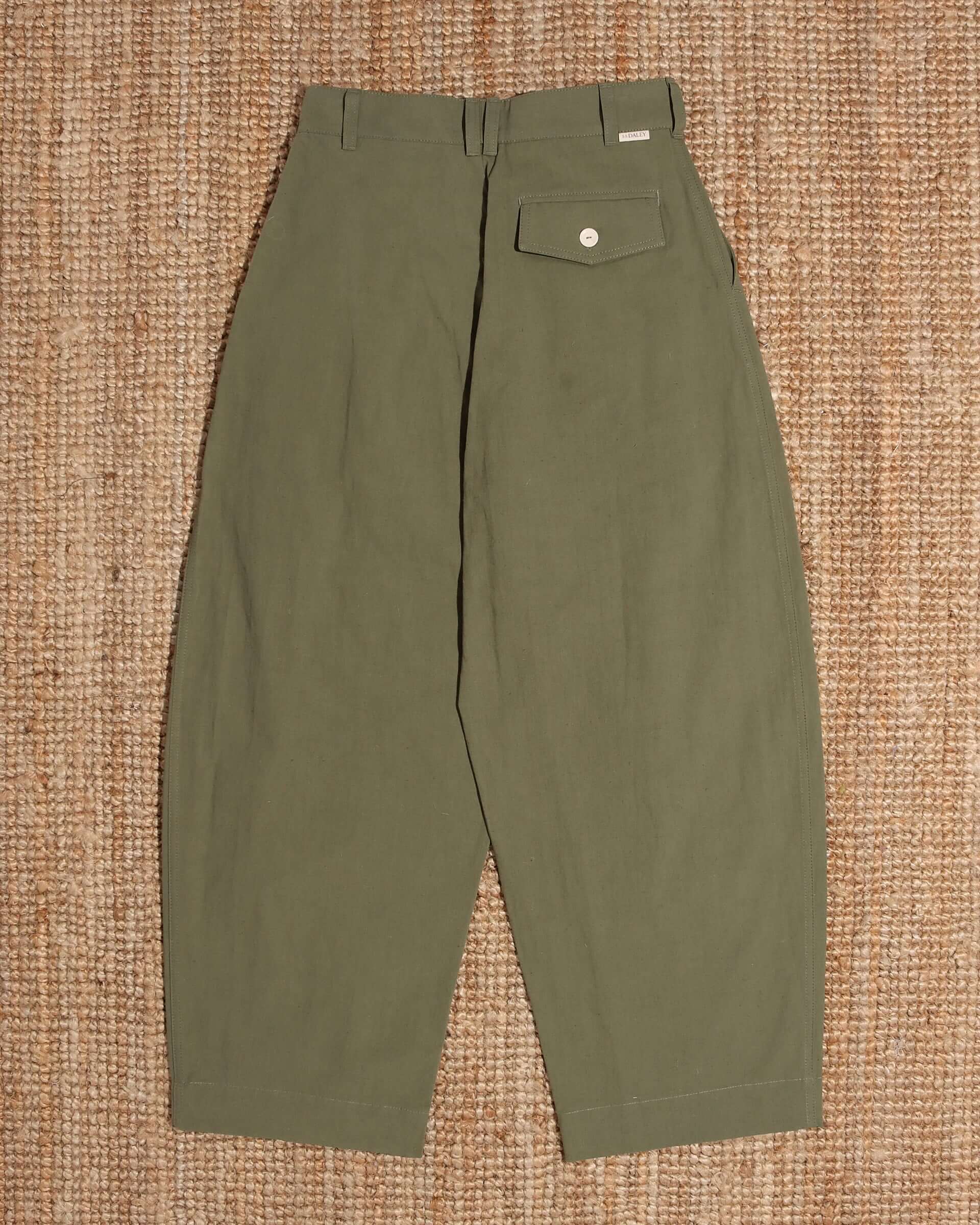 A flat shot of the back of the 'Clarence' Trouser in khaki green, showing the rounded legs, and right side back pocket with a white button closure.