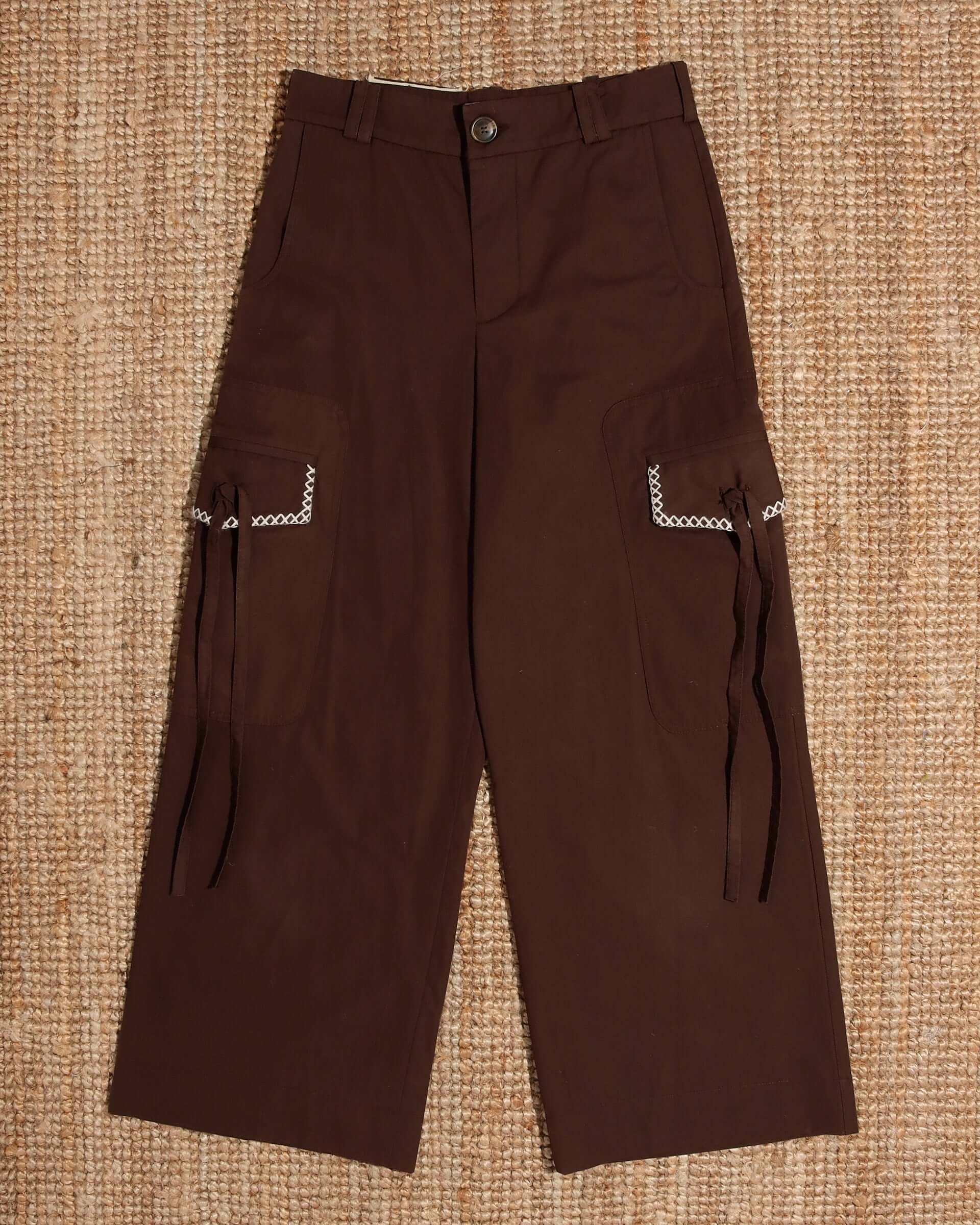 A flat image of the 'Milton' Cargo Trouser in brown with double pockets with a white crochet and tie detail.