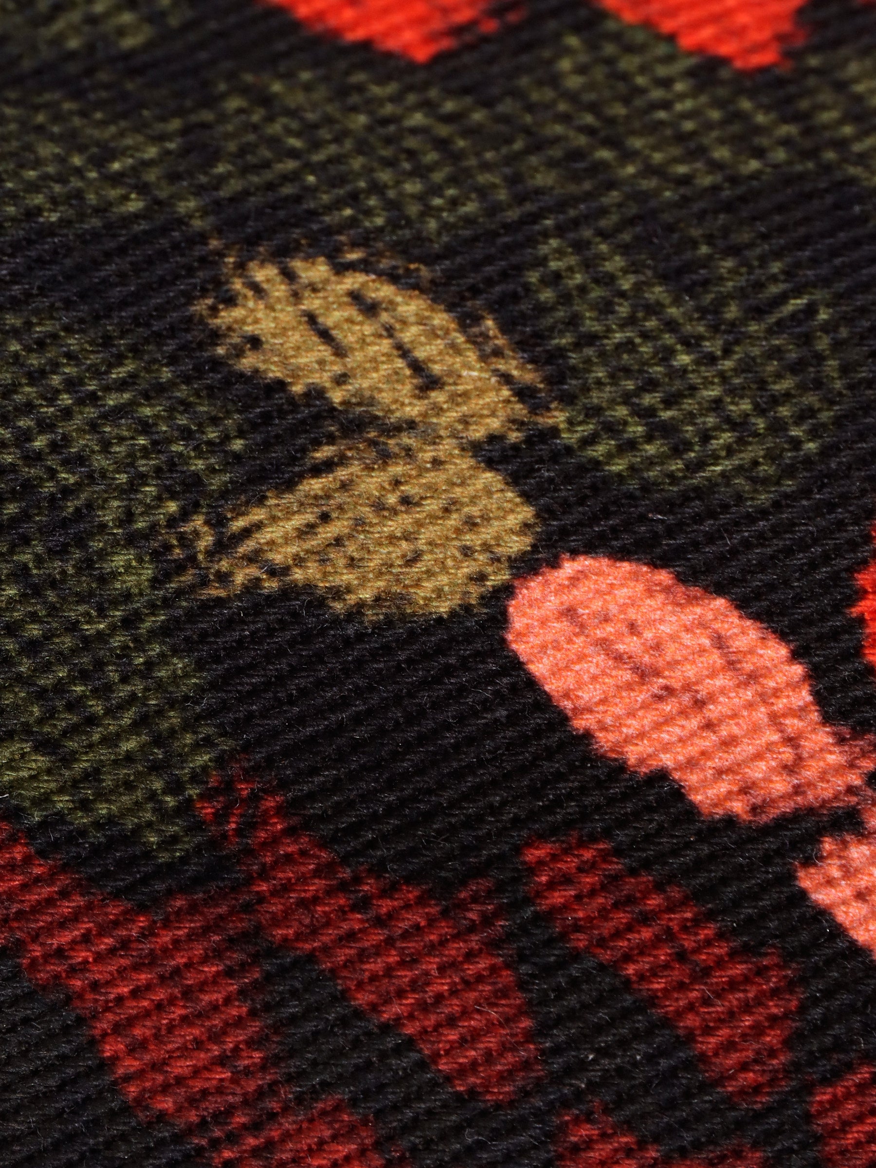 Close-up of the 'Spry' Trouser's floral patterned fabric with red, green, and black colours. 