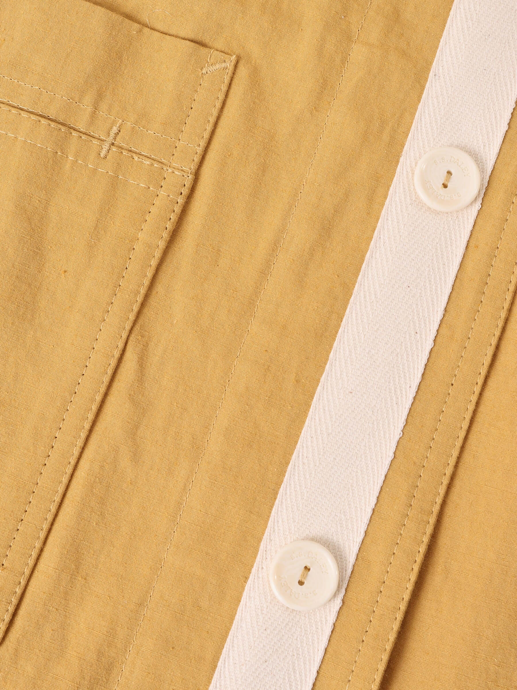 A close-up of the Japanese technical cotton-blend fabric in mustard and ecru herringbone cotton tape detail applied to the front placket.