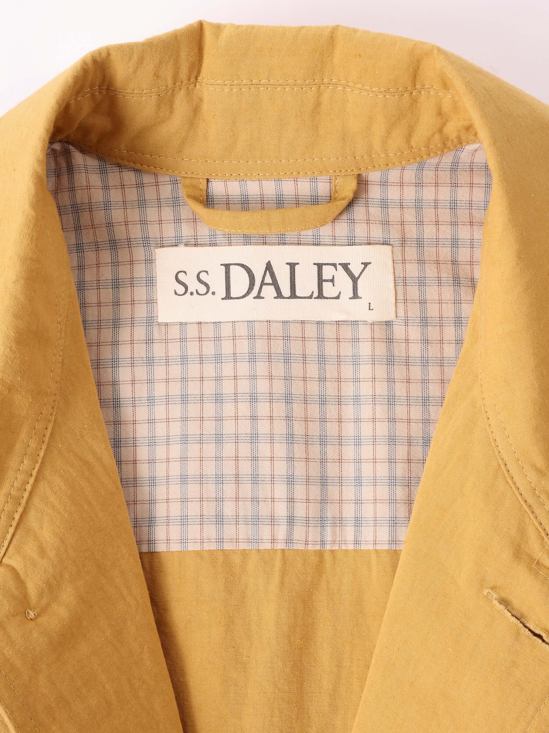 A close-up of the 'Clarence' Chore Jacket in mustards S.S.DALEY label and check lining as well as it's jacket loop.