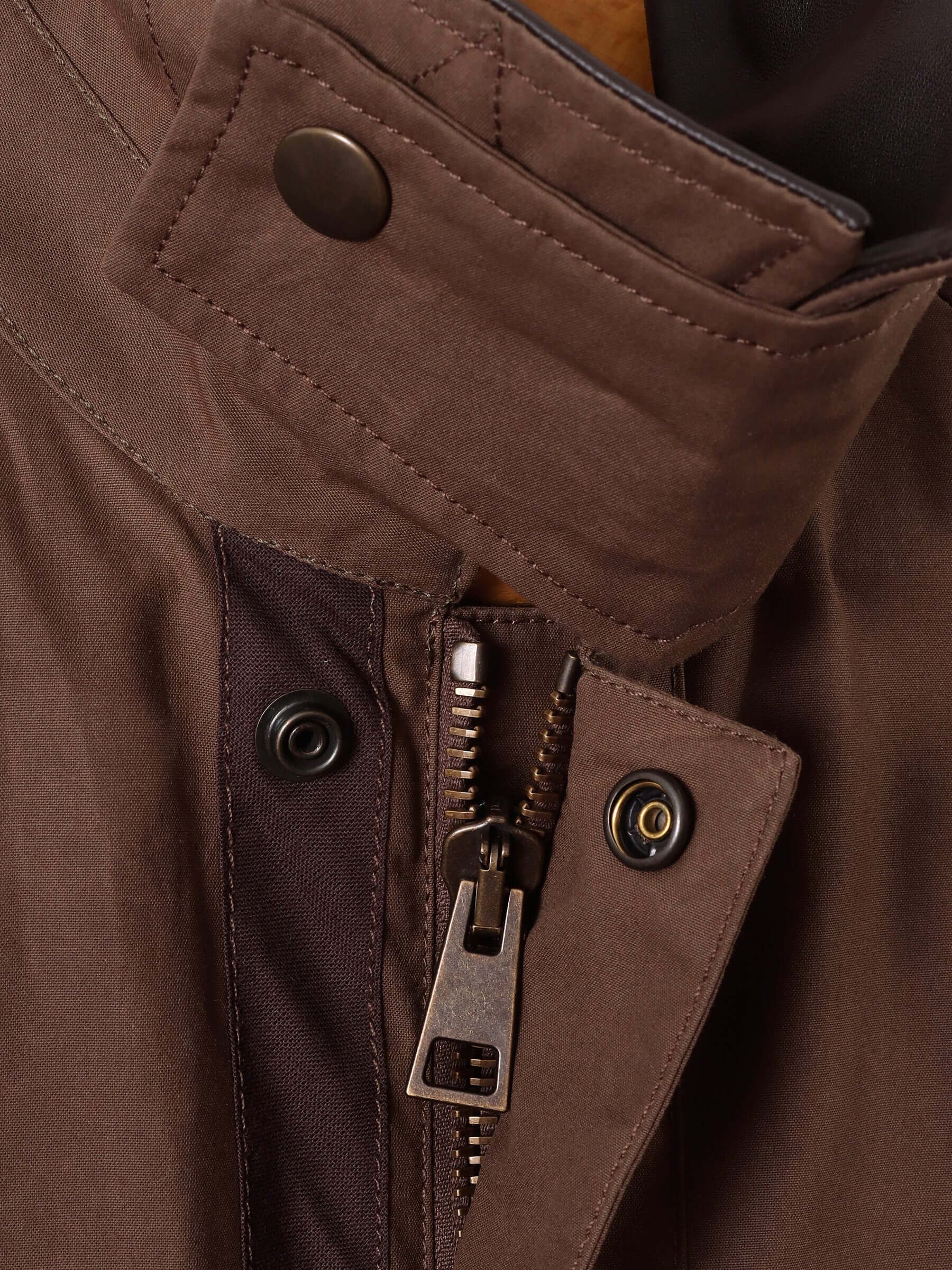 A close up of the brown wax jacket material and the snap-close throat-latch.