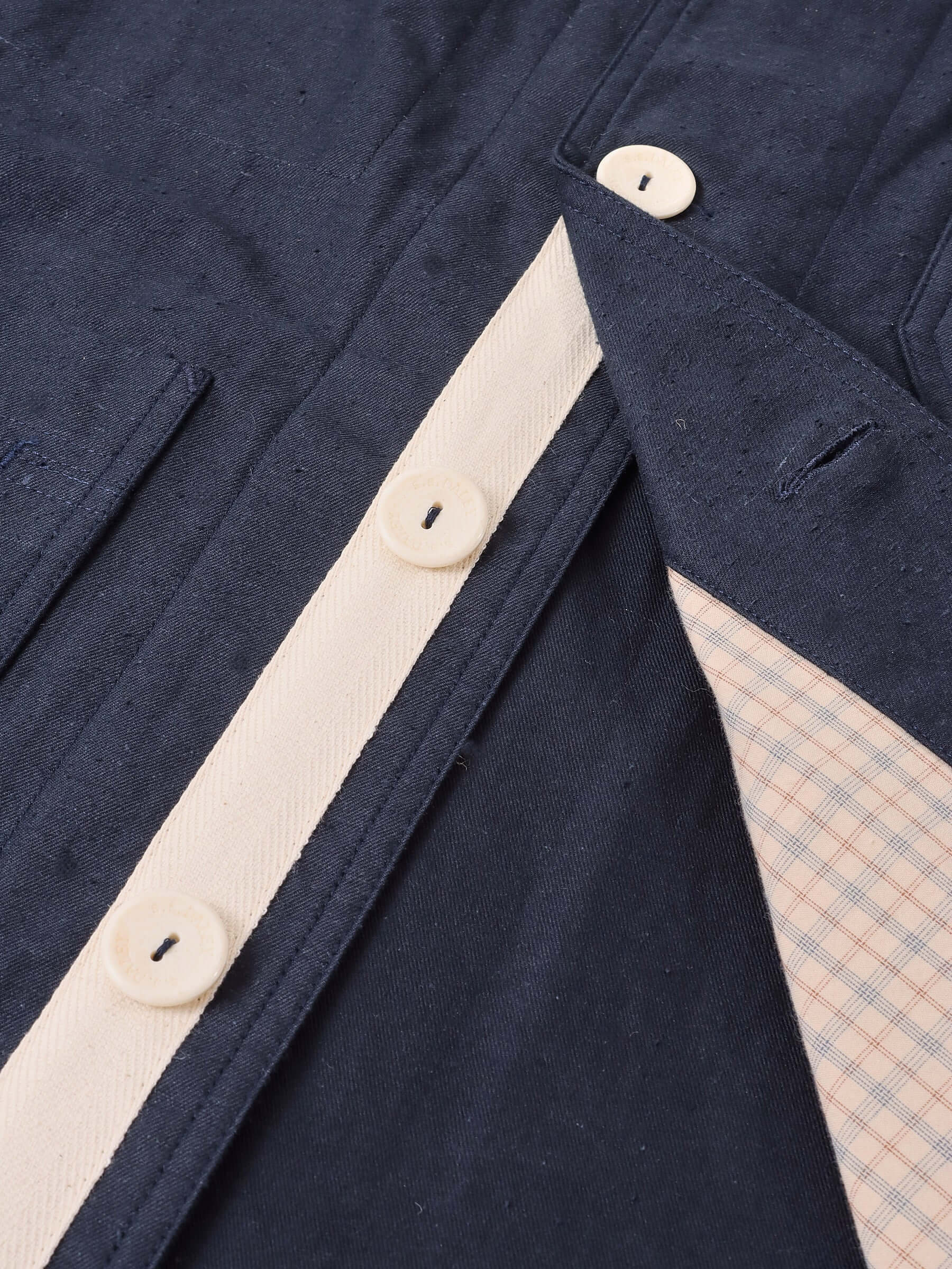 A close up of the navy Japanese cotton-blend and interior check fabric, and the  interior placket with ecru herringbone tape and ecru buttons.
